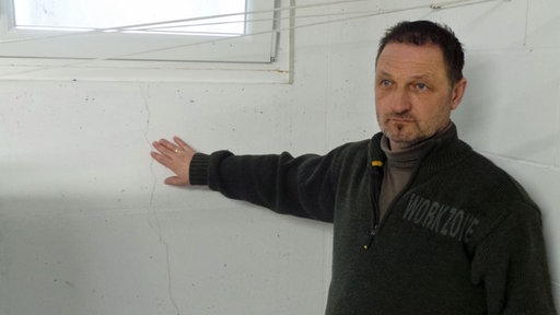 Thomas Kottig vor einer weißen Kellerwand mit Rissen