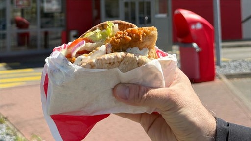 Eine Hand die den neuen "Krispy Kebab" von KFC hält