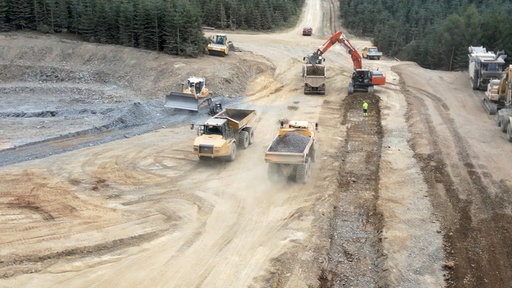 Eine große Baustelle im Wald mit Baggern, Muldenkippern und anderen Fahrzeugen