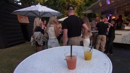Stehtisch mit Getränken auf dem Schützenfest in Iserlohn, im Hintergrund stehen einige Frauen mit einem Mann
