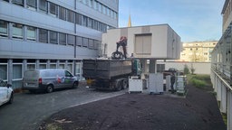 Ein LKW lädt hinter dem Hospital Schrott auf