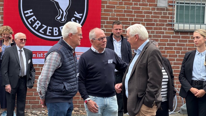 Bundespräsdent Steinmeier im Gespräch mit zwei Männern