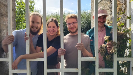Lachende, junge Menschen hinter siehen hinter einem Gitter