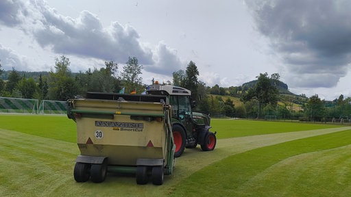 Ein Traktor fährt über den neuen Sportplatz.
