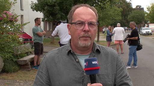 Oliver Köhler steht mit einem Mikro in der Hand am Ort der Festnahme