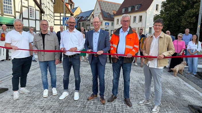Symbolisch wird ein Rotes Band zur wiedereröffnung durchtrennt