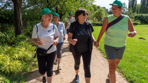 Eine Gruppe Frauen walkt durch einen Park.