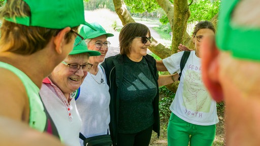 Eine Gruppe Personen liegt sich im Arm