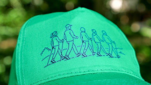 Eine grüne Baseball-Kappe mit einer Wandergruppe als Stickerei.