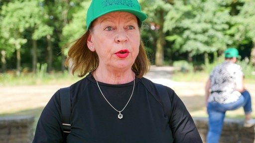Eine Frau mit grüner Baseball-Kappe im Porträt.