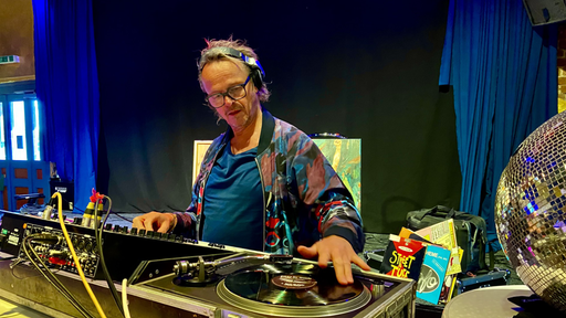 Ein DJ mit langen blonden Haare legt Vinylplatten auf.