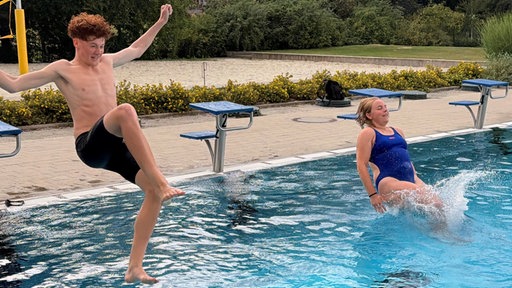 Zwei Jugendliche springen in ein Schwimmbecken