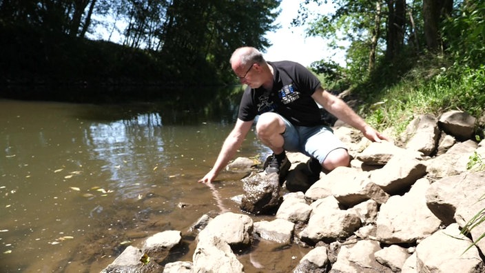 Jemand streckt seine hand ins Wasser und fühlt die Temperatur