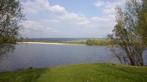 Blick von einem grünen Ufer über den Godelheimer See bei Höxter
