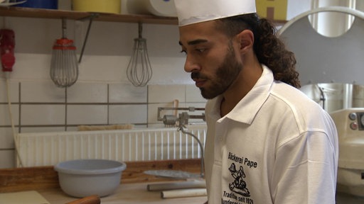 Ahmad ist konzentriert bei der Arbeit. Er faltet gerade Blätterteig.