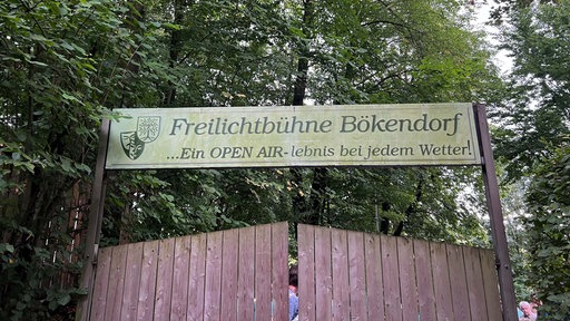 Eingangsschild über einem hohen Holztor