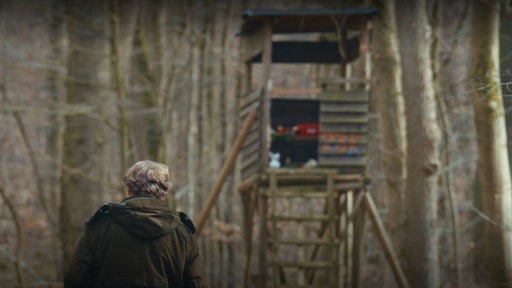 Ein Jäger vor einem Hochsitz