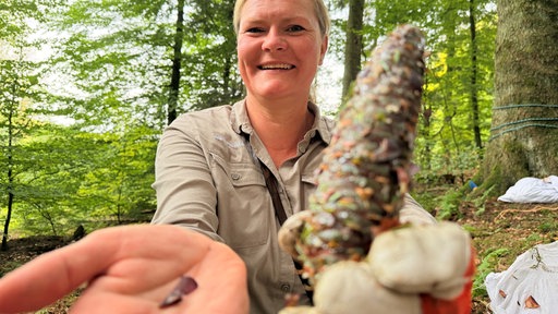 Frau hält Zapfen und Samen in die Kamera