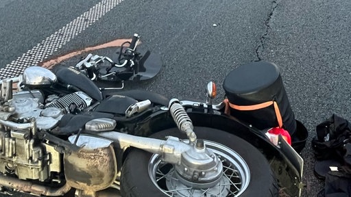ein Motorrad mit Unfallspuren liegt auf einer Straße