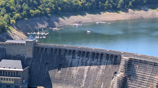 Hinter einer Staumauer sieht man den niedrigen Wasserstand in einer Talsperre.