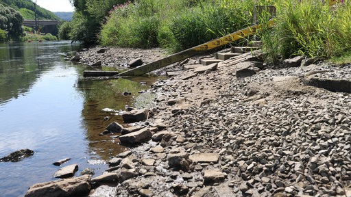 Hinter einer Staumauer sieht man den niedrigen Wasserstand in einem See.