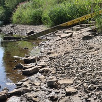 Hinter einer Staumauer sieht man den niedrigen Wasserstand in einem See.