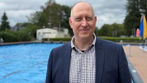 Ein Mann vor einem Schwimmbecken im Porträt
