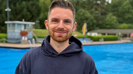 Ein junger Mann vor einem Freibad im Porträt