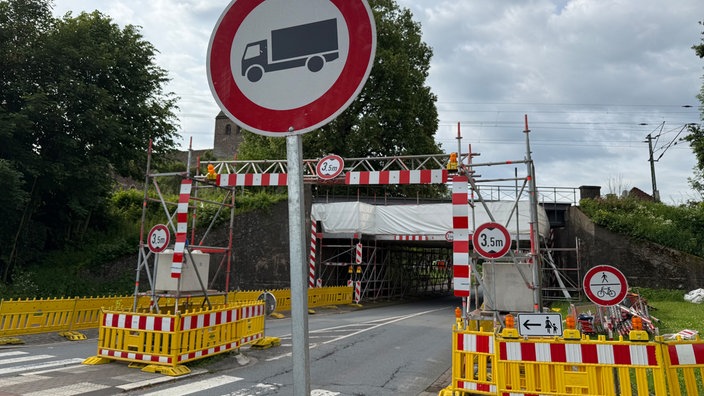 Absperrungen und Hinweisschilder zur Höhenbegrenzung vor der Eisenbahnbrücke in Lüdge
