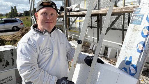 Ein junger Mann mit Behinderung arbeitet auf einer Baustelle.