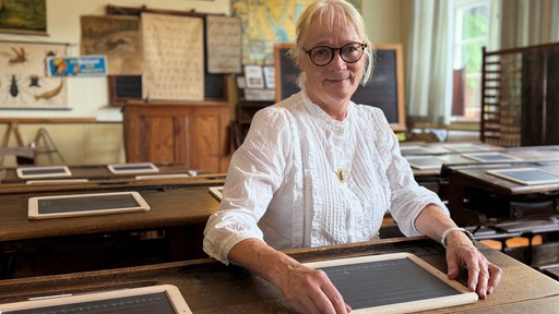 Lehrerin sitzt am Schulpult