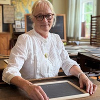 Lehrerin sitzt am Schulpult