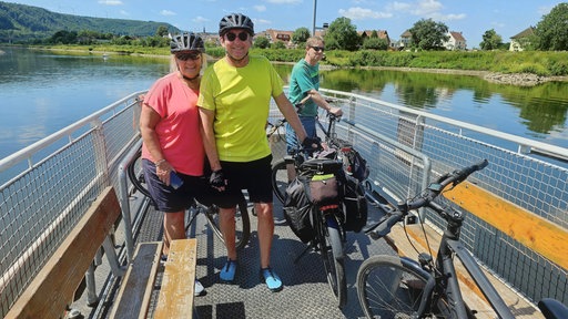 Antje und Johann Ahollinger aus der Nähe vom Bamberg (Bayern), die gerade auf einer Fähre in Beverungen-Herstelle die Weser überqueren.