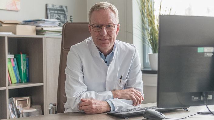  Dr. Peter Witte sitzt an seinem Schreibtisch und blickt in die Kamera