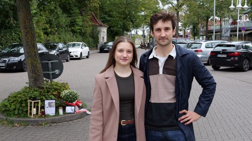 Ferris und Stella Fechner knien vor einer Kerze am Bahnhofsparkplatz in Bad Oeynhausen.