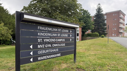 Es sind Wegweiser zu sehen auf denen die Richtung zur Frauen- und Kinderklinik St. Louise Paderborn angezeigt wird. Im Hintergrund Gebäude.