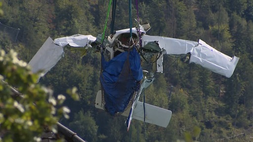 Ein Flugzeugwrack hängt an einem Seil