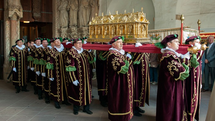 Menschen in Gewändern tragen bei der Prozession des Libori Festes den goldenen Libor-Schrein