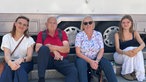 Vier Personen sitzen auf einer Treppenstufe vor einem LKW