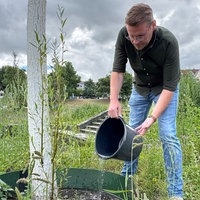 Stefan Buschmeier gießt einen der 32 neu gepflanzten Bäume im Paderquellgebiet.