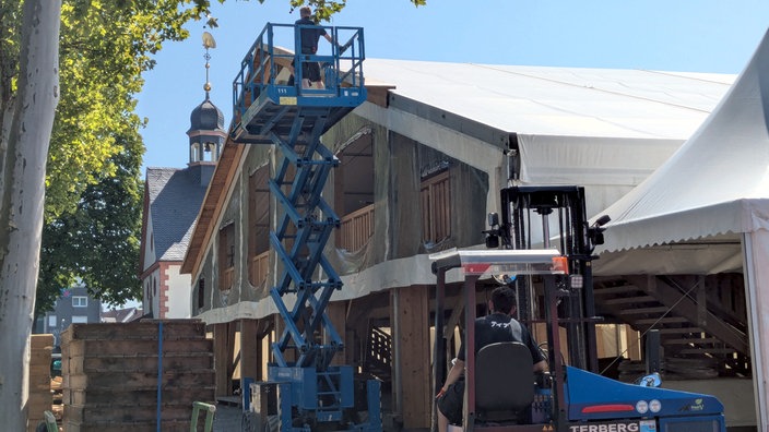 Das große Libori Festzelt wird noch aufgebaut. Auf einer Hebebühne werkeln zwei Arbeiter. In einem Gabelstapler wartet ein weiterer Arbeiter auf seinen Einsatz.