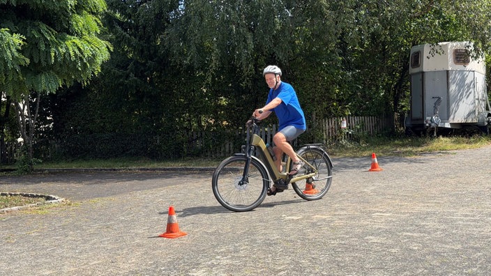 Fahrradfahrer fährt Slalon um Pylonen.