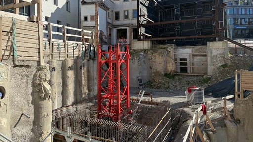 Ein rotes Baugerüst in einer Baugrube.