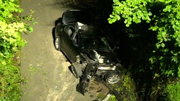 Ein zerstörtes Auto liegt auf einem Fahrradweg