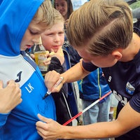 Ein Fußballspieler vom FC Paderborn schreibt sein Autogramm auf den Pulli eines jungen Fans.