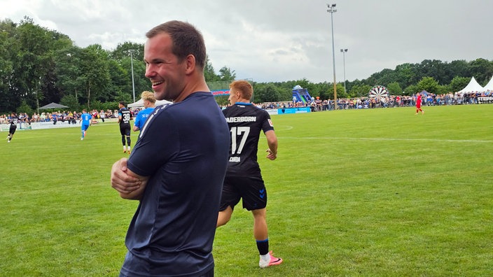 Ostenland Trainer Daniel Brökelmann schmunzelt am Rande des Spielfeldes.