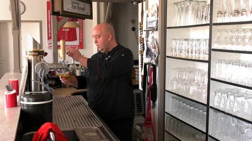 Gastwirt zapft Bier aus einem Fass