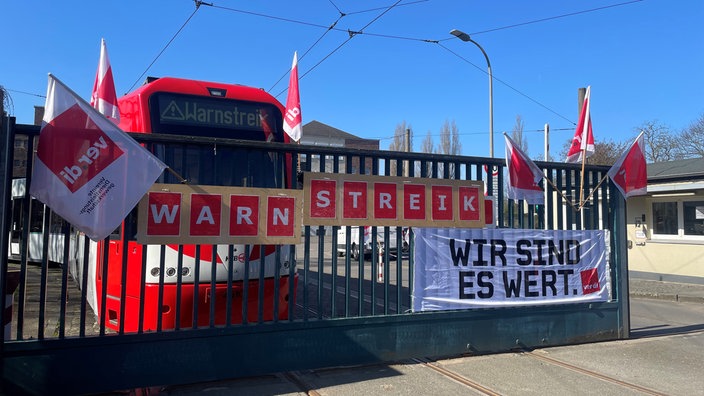 ein Bus hinter einem Zaun mit Streikplakaten