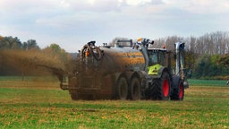 Ein Traktopr fährt über ein Feld und streut Düngemittel