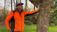 Ein Mann steht neben einem Baum.